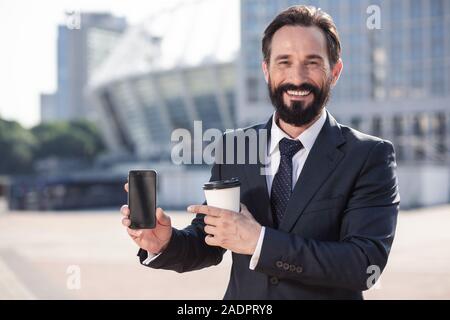 Fröhliche bärtigen Geschäftsmann mit einem modernen Smartphone Stockfoto