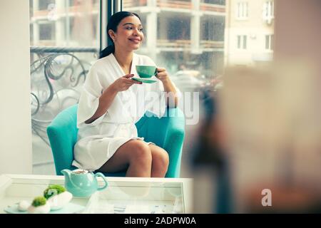 Junge Frau entspannen mit Tee im Sessel Stockfoto