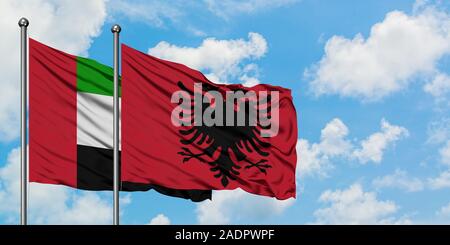 Vereinigte Arabische Emirate und Albanien Flagge im Wind gegen Weiße bewölkt blauer Himmel zusammen. Diplomatie Konzept, internationale Beziehungen. Stockfoto