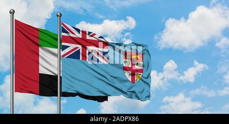 Vereinigte Arabische Emirate und Fidschi Flagge im Wind gegen Weiße bewölkt blauer Himmel zusammen. Diplomatie Konzept, internationale Beziehungen. Stockfoto