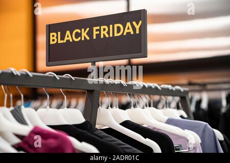 Big Verkauf Schwarzer Freitag. Rabatt Jahreszeit an der Kleiderkammer in der Mall. Eine Reihe von Halterungen mit bunten Kleidern. Unscharfer Hintergrund. Stockfoto