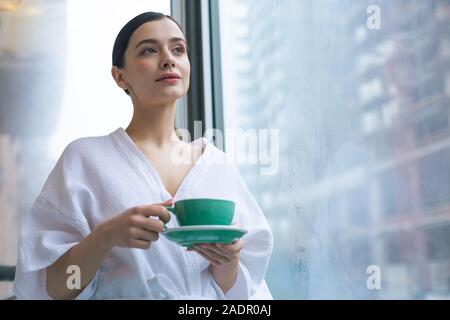 Schöne Frau in weißer Bademantel mit Tasse Tee Stockfoto