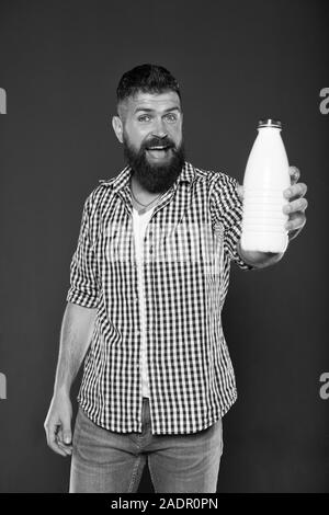 Das beste Getränk für Ihren Körper. Der bärtige Mann hält eine Flasche Milch trinken auf grauem Hintergrund. Happy hipster lächelnd mit natürlichen gesunden Milch trinken. Kaukasische Kerl genießen Sie frischen Joghurt Drink. Stockfoto