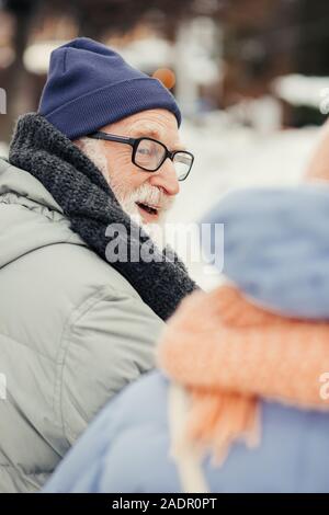 Bärtiger Mann mit Brille an die Person neben ihm lächelnd Stockfoto