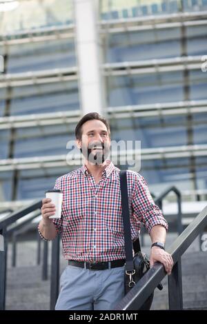 Lächelnd bärtiger Mann zu Fuß in den städtischen Einstellungen Stockfoto