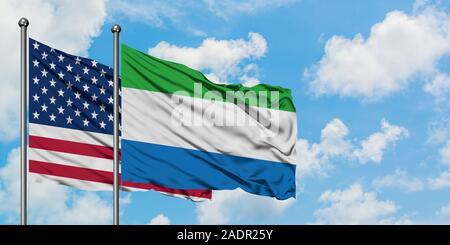 Vereinigten Staaten und Sierra Leone Flagge im Wind gegen Weiße bewölkt blauer Himmel zusammen. Diplomatie Konzept, internationale Beziehungen. Stockfoto