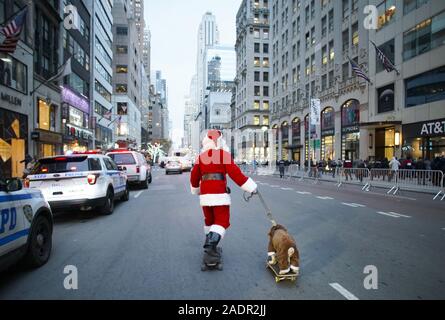 New York, Vereinigte Staaten. 04 Dez, 2019. Ein Mann wie Weihnachten Santa Claus Skateboards, die 5th Avenue mit einem Hund auch auf einem Skateboard vor der 87. jährlichen Zeremonie Weihnachtsbaum am Rockefeller Center in New York City am Mittwoch, 4. Dezember 2019 bekleidet. Foto von John angelillo/UPI Quelle: UPI/Alamy leben Nachrichten Stockfoto