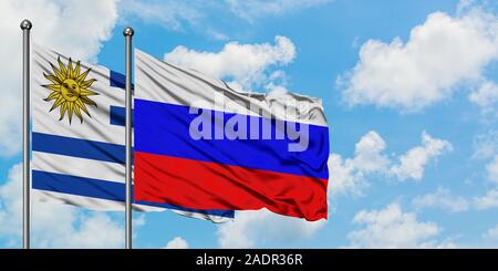 Uruguay und Russland Flagge im Wind gegen Weiße bewölkt blauer Himmel zusammen. Diplomatie Konzept, internationale Beziehungen. Stockfoto