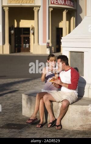 Junges Paar isst eine Pizzaschnitte - Junges Paar essen Pizza im Freien Stockfoto
