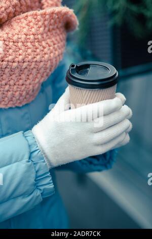Hände in warme Handschuhe holding Karton Tasse Kaffee Stockfoto