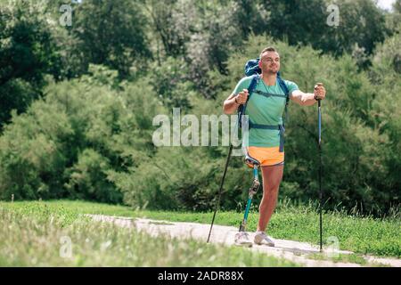 Handicap Mann genießen Sie Nordic Walking im Freien begeistert Stockfoto