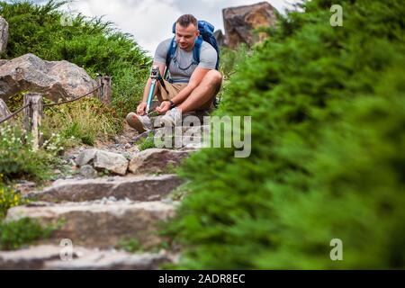 Angenehme Mann mit Prothese sitzt auf der steinernen Treppe im Freien Stockfoto