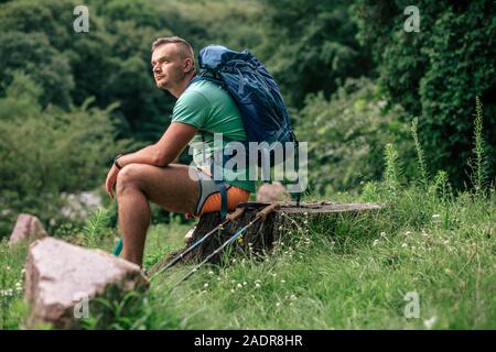 Ernster Mann mit Prothese sitzt auf dem Baumstumpf Stockfoto