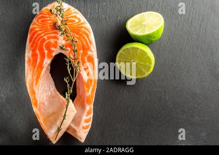 Rohe rote Lachs mit Thymian und die beiden Hälften des Limes in der Nähe von Stockfoto