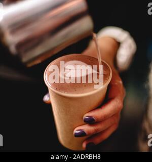 Weibliche barista gießen Milch in Kaffee Herzform Stockfoto