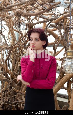 Mädchen in einem roten Hemd und Rock vor dem weißen Hintergrund von Bäumen Stockfoto