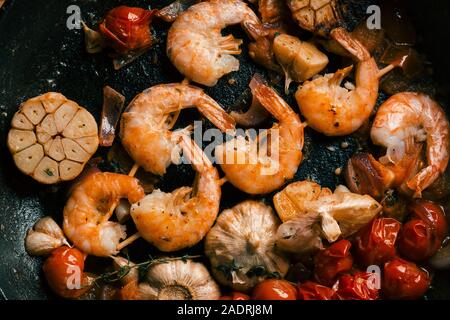 Schwarze Pfanne mit Garnelen und Gemüse auf es Stockfoto