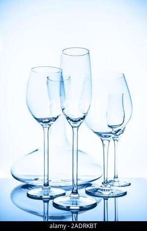 Glaswaren Auswahl mit Wein, Sekt, liquour Gläser und Dekanter auf dem hellen Hintergrund in blau Toning. Feine cristal Glaswaren Konzept. Vertikale. Stockfoto