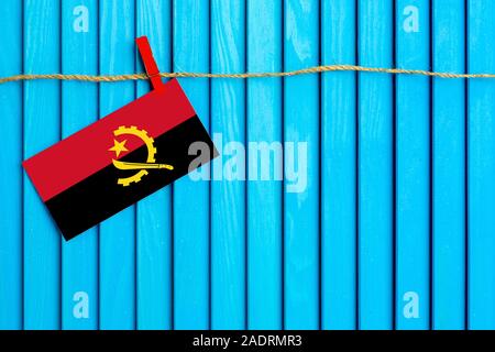 Flagge von Angola hängen auf Wäscheleine mit Holz Wäscheklammern auf aqua blau Holz- Hintergrund geklebt. Nationalen Tag Konzept. Stockfoto