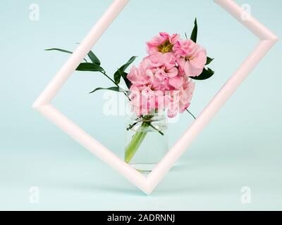 Weißer Landschafts-Rahmen-Mockup mit Blumen in stilvoller Vase in der Nähe der blauen Wand. Leerer Rahmen für Präsentationsdesign. Schablonenrahmen für moderne Kunst Stockfoto