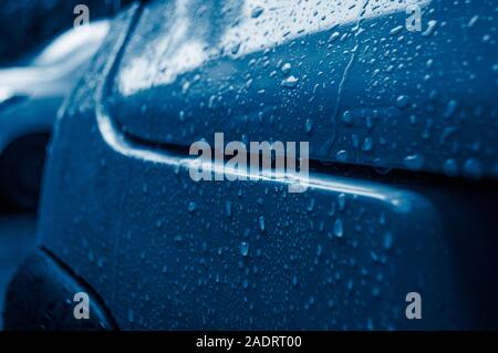 Schönen Regen fällt auf das Auto von trendigen Blau. Nasse Karosserie der angesagten Farbe Blau. 2020 color Trend. Stockfoto