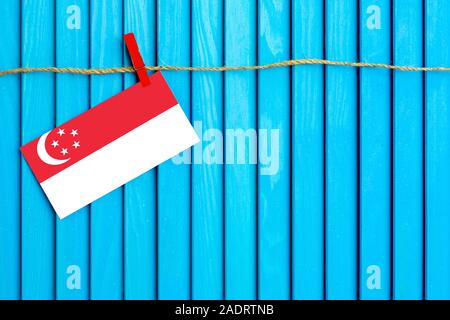 Flagge Singapur hängen auf Wäscheleine mit Holz Wäscheklammern auf aqua blau Holz- Hintergrund geklebt. Nationalen Tag Konzept. Stockfoto