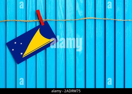 Flagge von Tokelau hängen auf Wäscheleine mit Holz Wäscheklammern auf aqua blau Holz- Hintergrund geklebt. Nationalen Tag Konzept. Stockfoto