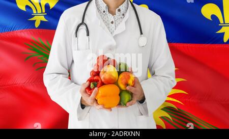 Arzt hält Sie Obst und Gemüse in die Hände mit Guadeloupe Flagge Hintergrund. Nationalen Gesundheitswesen Konzept, medizinische Thema. Stockfoto