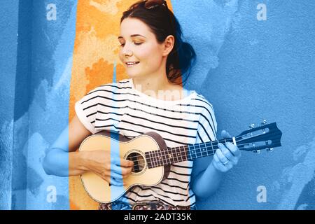 Mädchen mit Gitarre ukulele auf der Wand Hintergrund Stockfoto