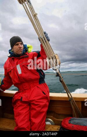 Ein Mann mit einer Klage auf einem Segelboot in arktischen Gewässern. Nautische Sicherheit Stockfoto