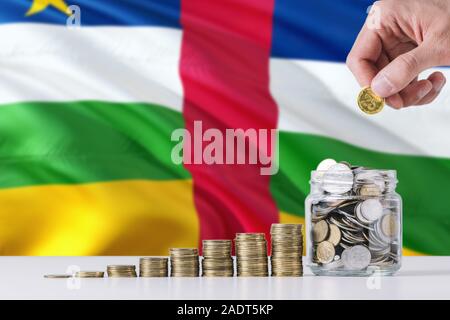 Business Mann mit Münzen, Glas, Zentralafrikanische Republik Flagge schwenkten im Hintergrund. Finanzen und Business Konzept. Spart Geld. Stockfoto