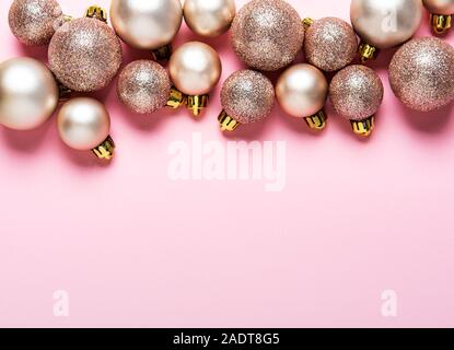 Weihnachtskugeln Hintergrund. Rose Gold und Silber Spielzeug Kugeln auf Pastell rosa Hintergrund. Festliche Dekoration, Flach, Ansicht von oben. Stockfoto