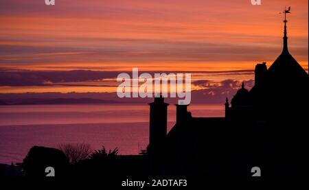 Lyme Regis, Dorset, Großbritannien. 5. Dezember 2019. UK Wetter: Schöne winter Sonnenaufgang in Lyme Regis. Gebäude und Bäume sind gegen die wunderschöne Farben im Himmel auf einer kühlen Morgen. Credit: Celia McMahon/Alamy Leben Nachrichten. Stockfoto