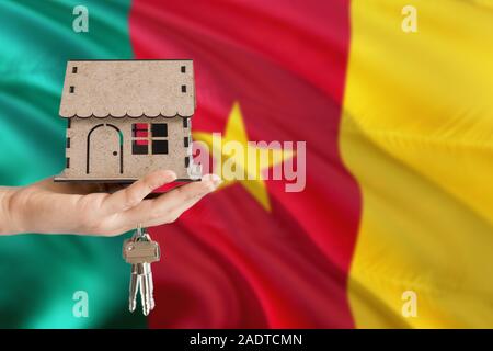 Frau hand Holz- haus und Tasten mit Hand. Kamerun Flagge mit Konzept der Miete, Kauf, Versicherung, Gebäude, Immobilien, eco-Haus. Stockfoto