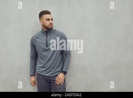 Bärtiger Kerl in Sportkleidung auf grauem Hintergrund. Stockfoto