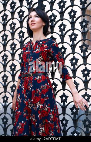 Schöne elegante Frau in der Nähe von Black posing schmiedeeisernen Toren Stockfoto