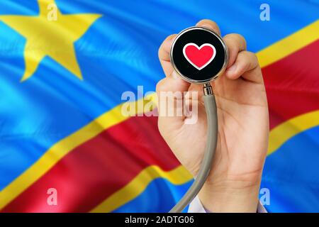 Arzt holding Stethoskop mit roten Liebe Herz. Nationale Kongo Flagge Hintergrund. Healthcare System Konzept, medizinische Thema. Stockfoto