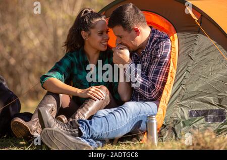 Freund küsst die Hand seiner Freundin vor dem Zelt. Fröhliche Atmosphäre Stockfoto