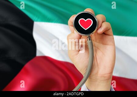 Arzt holding Stethoskop mit roten Liebe Herz. Nationale Kuwait Flagge Hintergrund. Healthcare System Konzept, medizinische Thema. Stockfoto