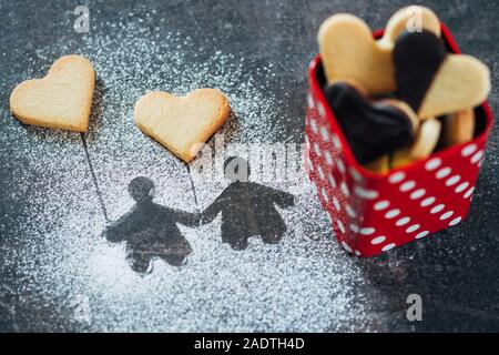 Herzförmige Plätzchen und liebevolles Paar Form Kontur von Weißzucker für den Hintergrund. Valentines Tag oder Weihnachten Thema Stockfoto