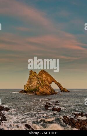 Bogen GEIGE ROCK PORTKNOCKIE Moray in Schottland WINTER SONNENUNTERGANG mit rosa Wolken und Schaum auf den Felsen Stockfoto