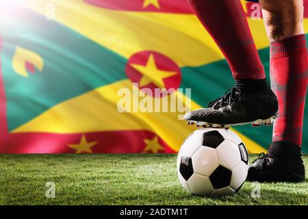 Nahaufnahme Beine von Grenada Fußballmannschaft Spieler in roten Socken, Schuhe auf Fußball im Free Kick oder elfmeterpunkt Spielen auf Gras. Stockfoto