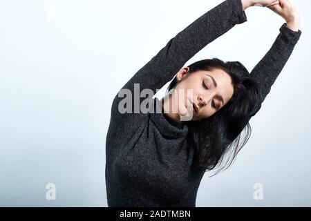 Kaukasische junge Frau erstreckt sich mit geschlossenen Augen, Hände Stockfoto