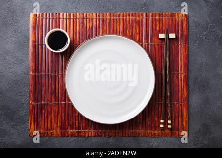 Asiatische Tisch Ambiente mit weißen Platte, Sauce Schüssel und Stäbchen. Ansicht von oben. Platz kopieren Stockfoto