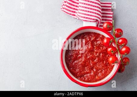 Traditionelle Tomatensauce in Kochtopf. Grauer Hintergrund. Ansicht von oben. Platz kopieren Stockfoto