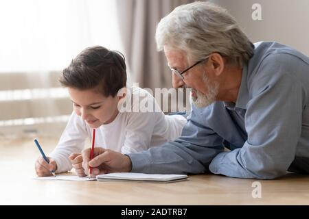 Großvater mit Enkel mit Buntstifte liegen auf dem Boden Stockfoto