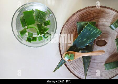 Aloe Vera Blätter auf einem Bambus Löffel und in ein Glas mit Wasser auf einem weißen Hintergrund. Medizin und Pflege. Stockfoto