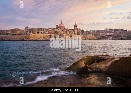 Malta. Valletta direkt am Meer bei Sonnenuntergang mit Basilika Unserer Lieben Frau vom Berge Karmel, gesehen von Sliema. Stockfoto