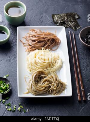 Sortiment japanischer Soba Nudeln mit Sauce und Beilagen. Schwarzer Schiefer Hintergrund Stockfoto