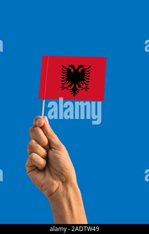 Frau Hand, die Albanien Flagge mit Stick, wehende Flagge auf tief blauen Himmel. Die nationalen Thema, tief blauen Himmel. Stockfoto